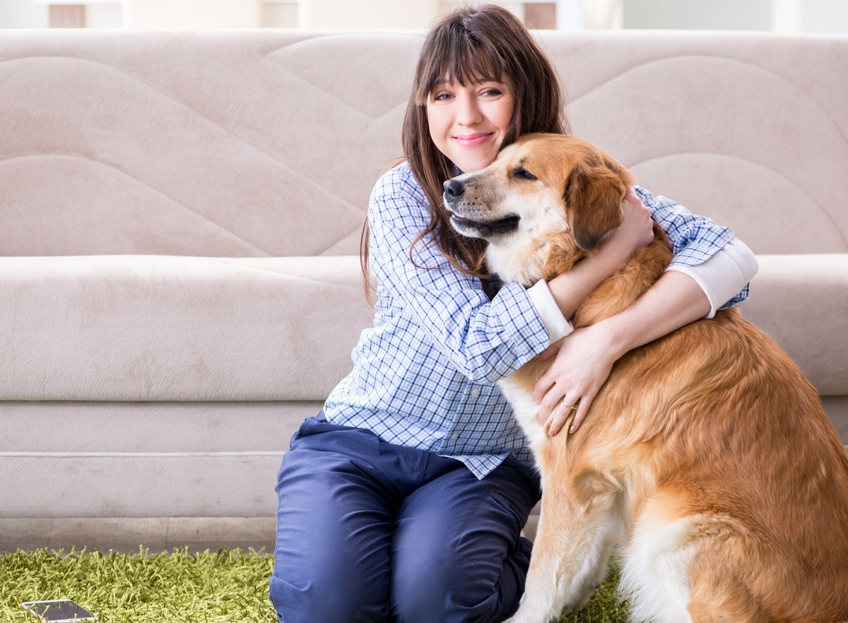 Woman hugging her golden retriever at home