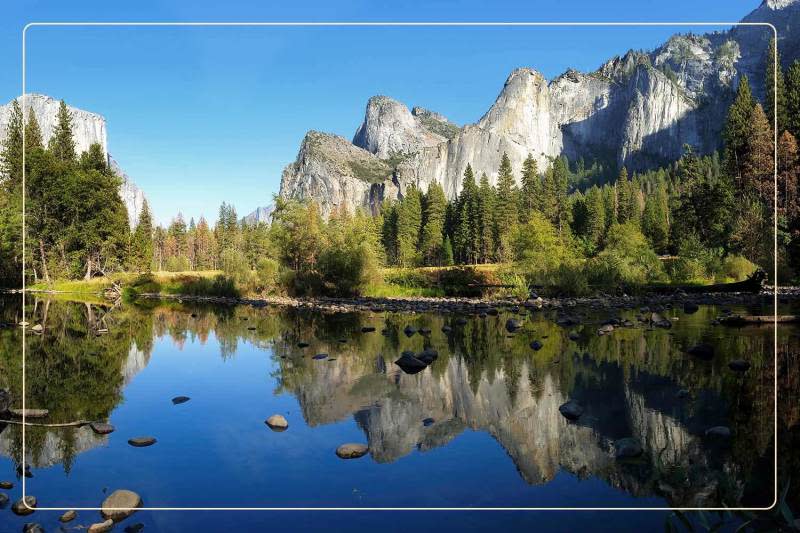a body of water below a mountain range in Yosemite National Park, a dog-friendly national park where one can go hiking with dogs