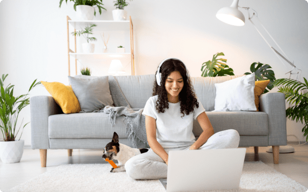 Woman searching on her computer with dog playing next to her
